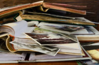 Nostalgia – old family photo albums and photos lie a heap on a wooden table.